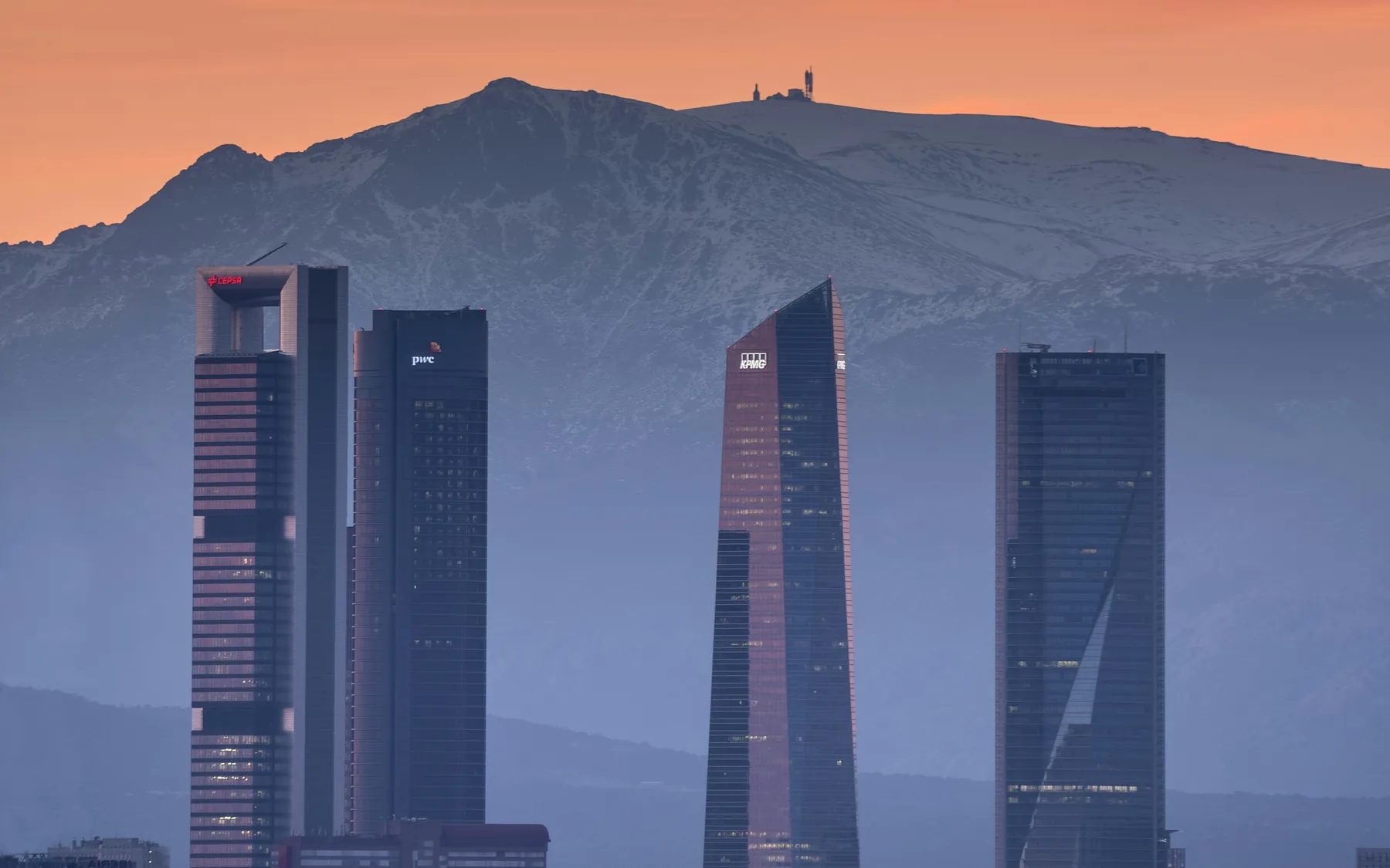 Las Cuatro Torres de Madrid al anochecer, con la sierra nevada al fondo